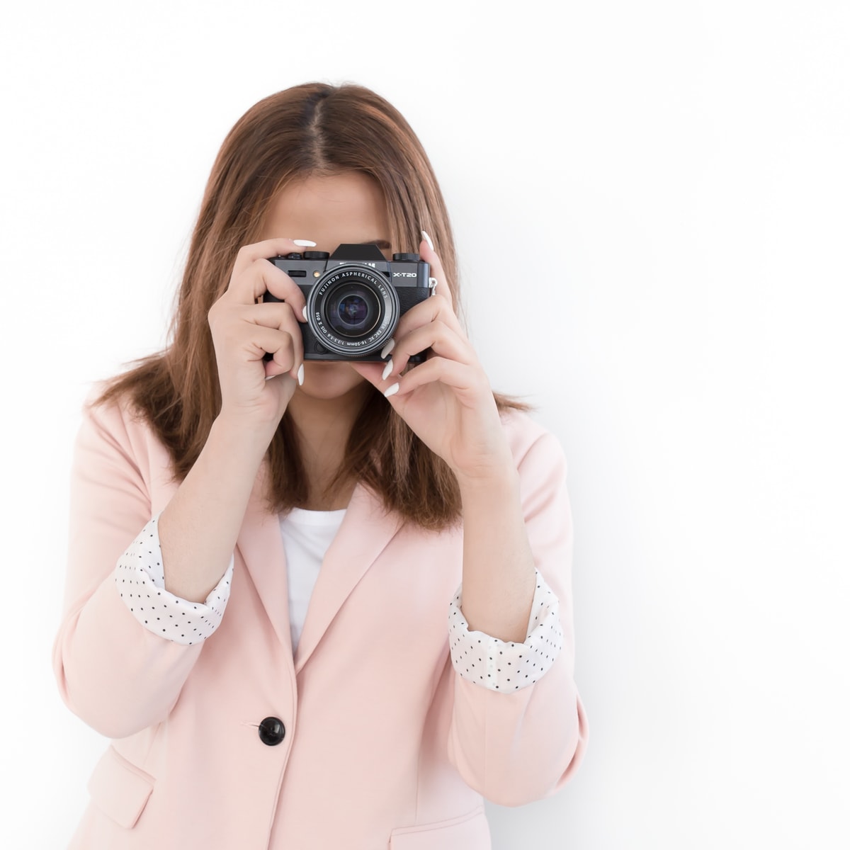 A woman wearing a pink jacket holding a camera to her face